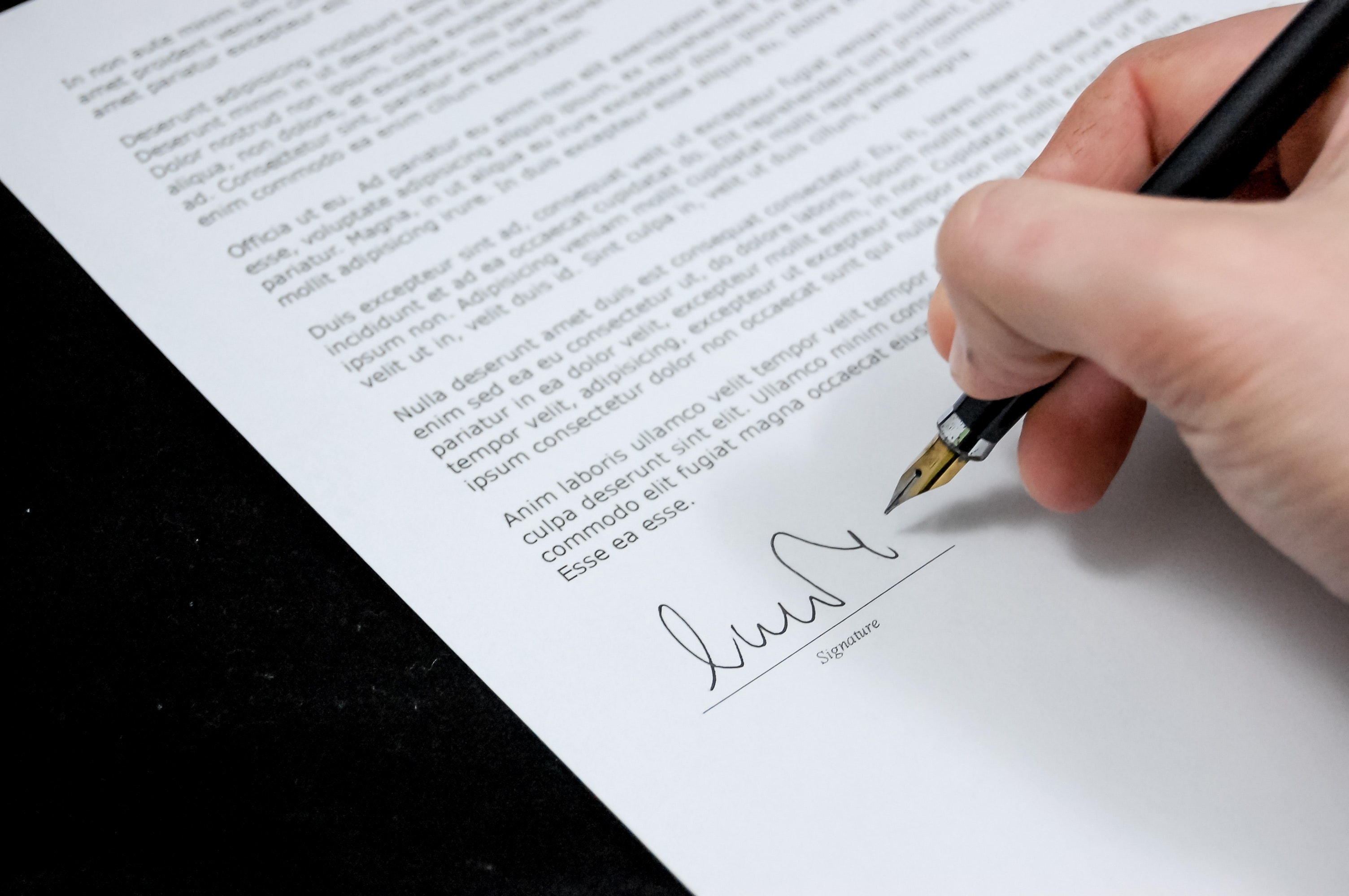 Male hand signing legal document with fountain pen