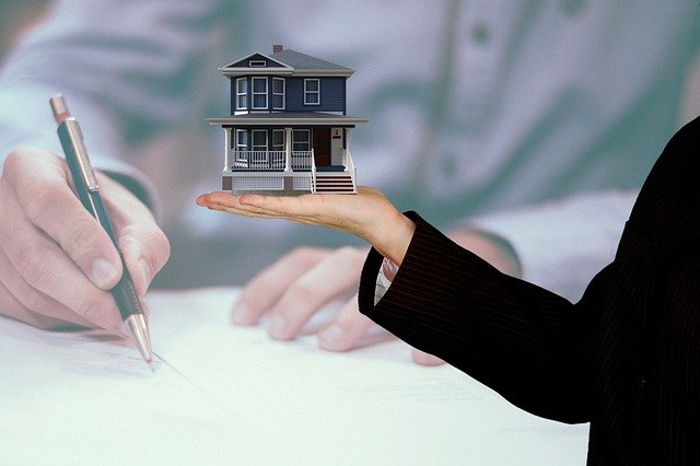 Image of Woman Holding a House over a Man Signing a Document
