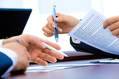 Hands Holding Pens Discussing Paperwork