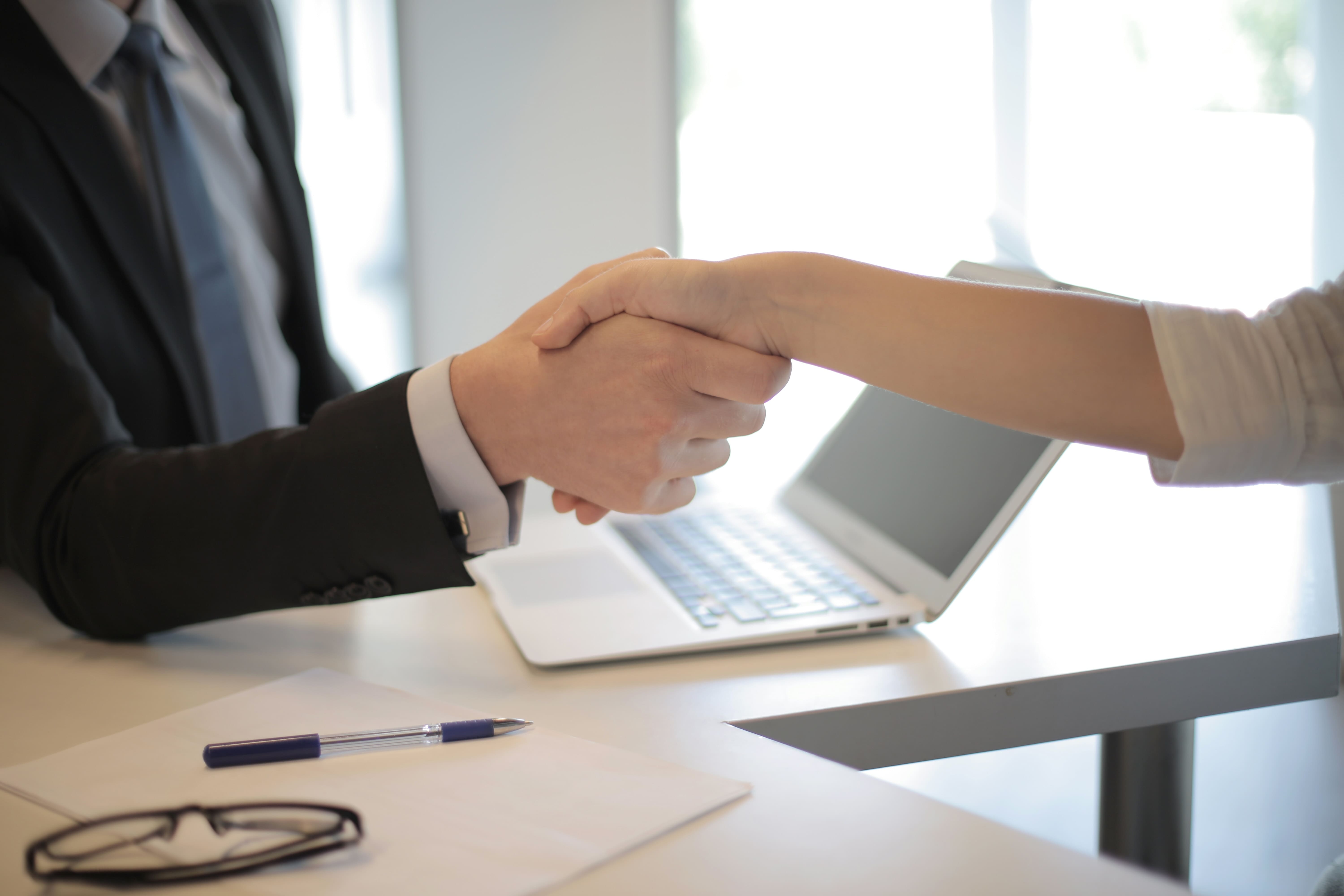 two people shaking hands at an office desk